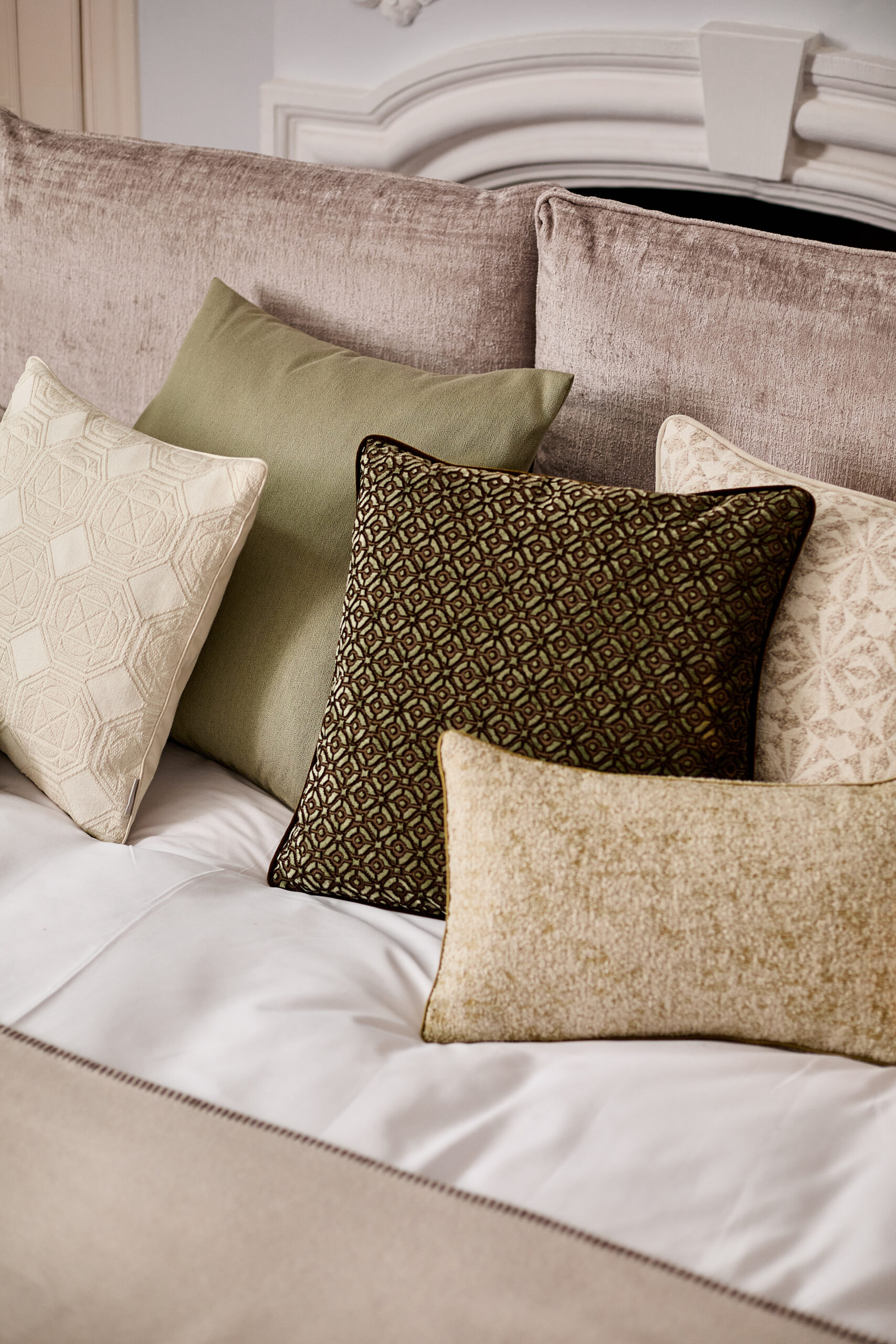 The New Chateau Kollektion von Designerin Lori Weitzner zeigt beigen und grüne Kissen auf einem beigen Bett
